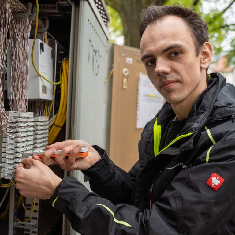Fachkraft bei Arbeiten an Netzwerktechnik und Telekommunikationsanlagen für moderne Glasfaser- und Datennetze.